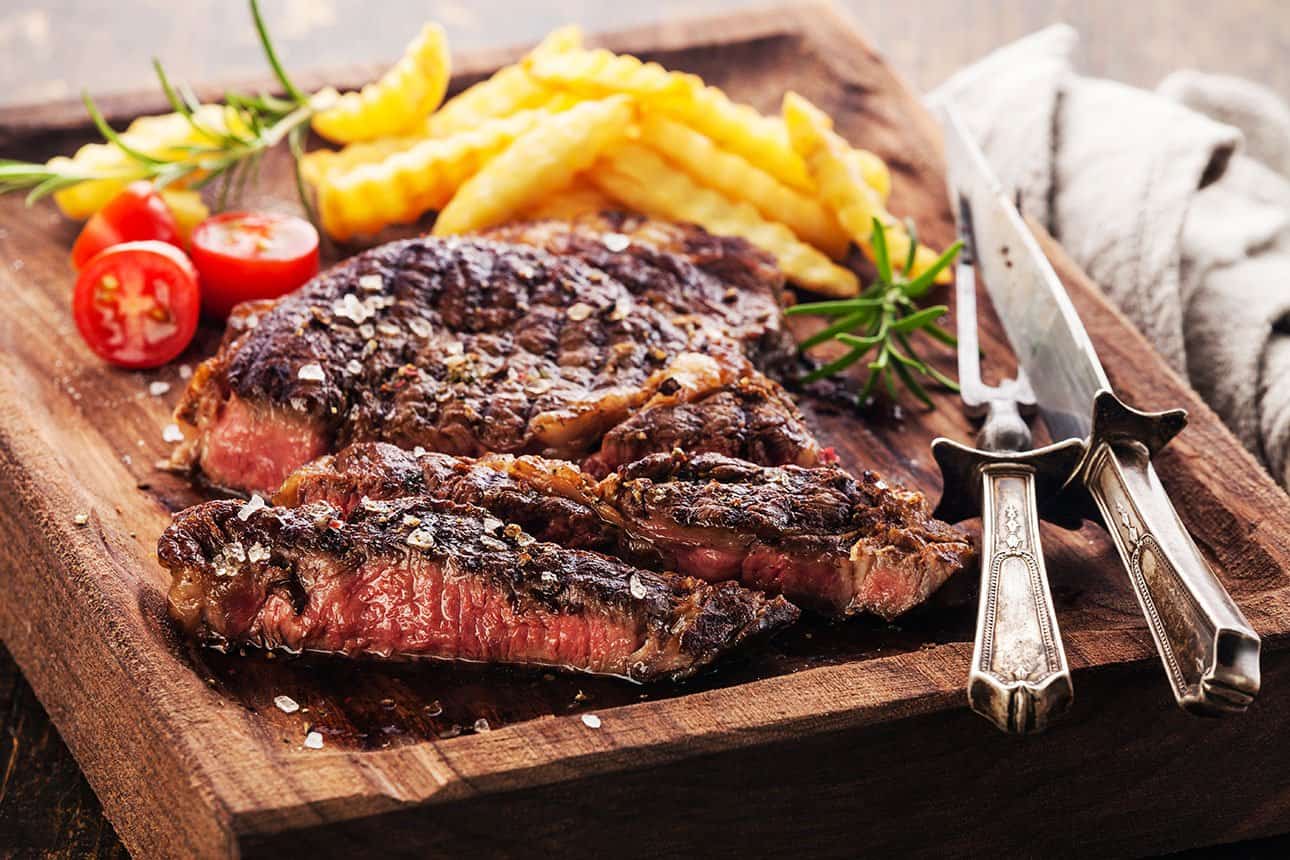 Saftiges Steak mit Pommes Frites auf Holzbrett