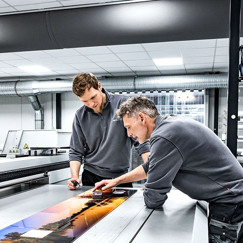Mitarbeiter von Printotec begutachten die Farben eines Digitaldruckes