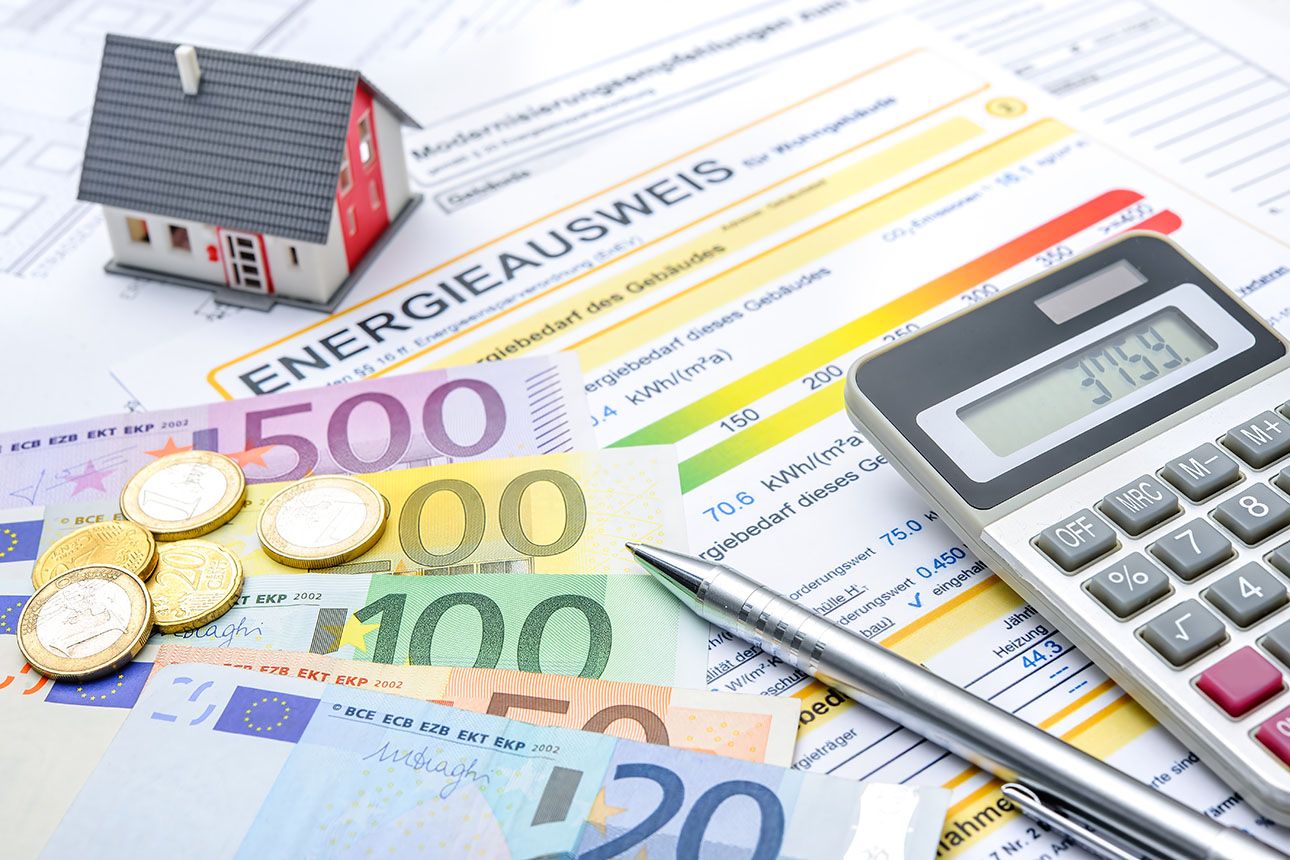 Foto von einem Energieausweis, daneben liegt Bargeld und ein Hausmodell