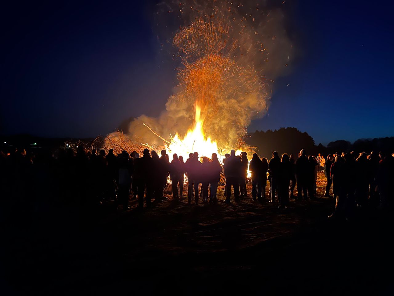 Menschen ringen sich um ein großes Osterfeuer