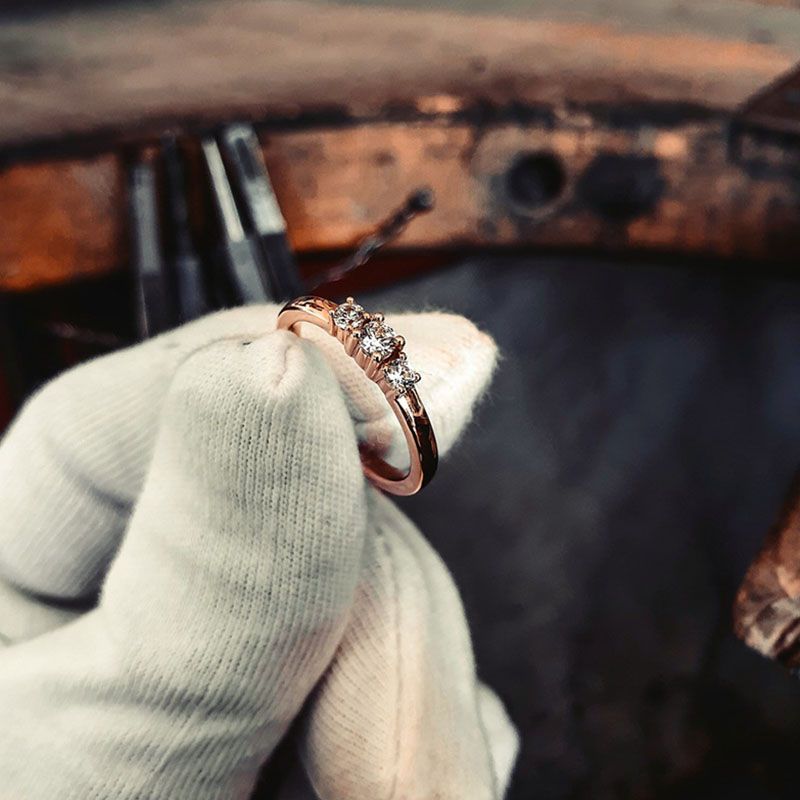 WasWoFinden PM Design Hamburg Atlanta Eine Hand mit weißen Baumwollhandschuhe hält einen goldenen Diamantring