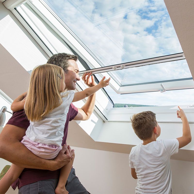 Mann mit Kind auf dem Arm am Insektenschutz für Velux Dachfenster